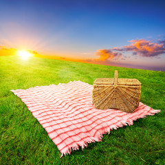 Picnic blanket and basket in a sunlit grassy meadow