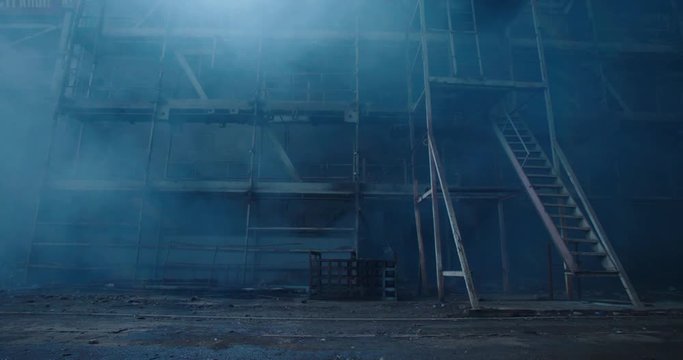 Old fabric manufactory building in the smoke. Dark Space atmosphere. Abandoned factory hall with broken glass on windows.Apocalyptic scene with destroyed warehouse.