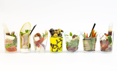 Mini desserts and meat canapes vegetable snacks in plastic cups canaps
