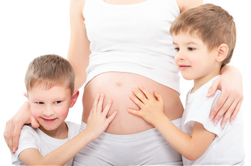 Two sons hugging belly pregnant mother