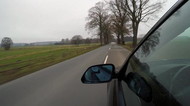 Black car driving on a country road on the evening - camera outside the driver's door