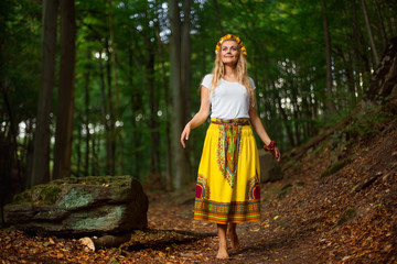 Beautiful blonde girl with long hair in national dress posing in green forest