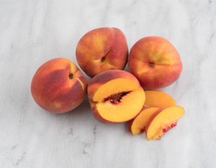 Whole nectarines with a slice on a gray marble cutting board.