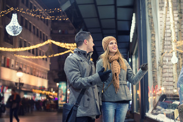 Obraz na płótnie Canvas Couple window shopping outdoors in winter city street.