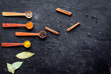 spices in wooden spoons on dark background top view