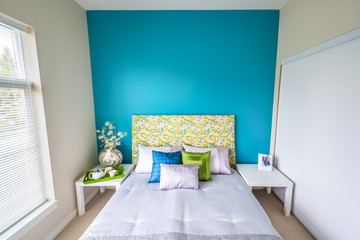 Modern blue bedroom interior with blue, green, and violet designer pillows in a luxury house. Interior design.