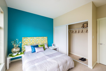 Modern blue bedroom interior with blue, green, and violet designer pillows in a luxury house. Interior design.
