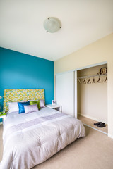 Modern blue bedroom interior with blue, green, and violet designer pillows in a luxury house. Interior design.