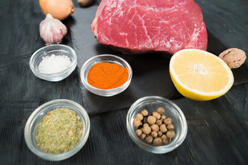 Raw beef steak on a cutting board with spices.
