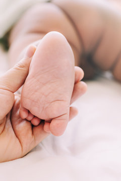 Close Up Mother Holding Newborn Feet and Massaging for Baby Care