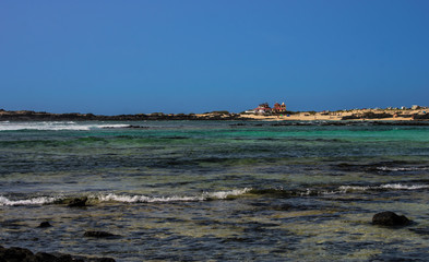 Fototapeta na wymiar spiaggia con onde, sabbia e rocce nere