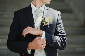 Groom buttons his shirt at the wedding