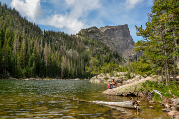 Naklejka premium female hiker sitting on the banks of Dream Lake with Hallett peak in the background Rocky Mountain National Park, Estes Park, Colorado, United States