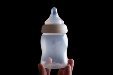 Handle baby bottle on black background.