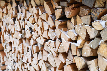 Wood under snow. Firewood for the winter. Chopped drovav folded.