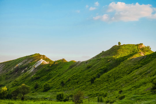 Green chalk hills under blue sky. The archaeological monument - Krapivinskaya settlement, Belgorod region, Russia.