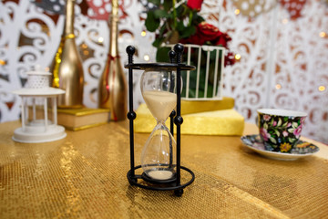 Hourglass on golden table symbolizing deadline of holidays. Time to celebrating