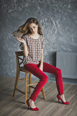 Young girl in red jeans was sitting on a chair 6936.