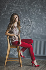 Young girl in red jeans was sitting on a chair 6945.