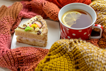 Cup of tea, lemon, chocolate, cake, dried fruits, yarn for knitting in the wooden table