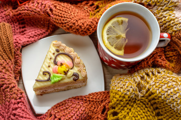 Cup of tea, lemon, chocolate, cake, dried fruits, yarn for knitting in the wooden table