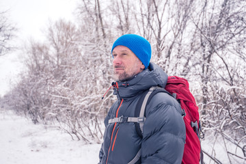 Bearded man with backpack in the winter forest