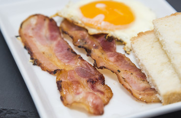 Fried egg and bacon slices plate