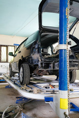 Black crashed car on stocks in a car repair station