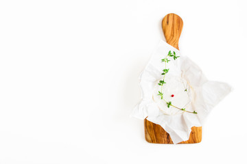 Camembert cheese and fresh thyme on cutting olive wooden board, flat lay, top view.