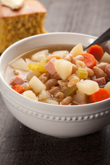 Ham and bean soup in a white bowl with corn bread