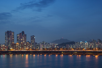 View of a lit residential district and bridge along the Han River in Seoul, South Korea, at night. Copy space.