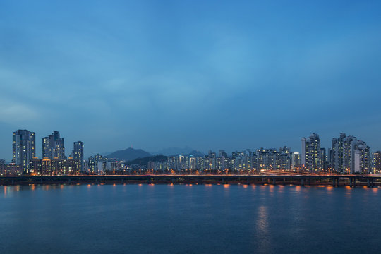 View of a lit residential district and bridge along the Han River in Seoul, South Korea, in the evening. Copy space.