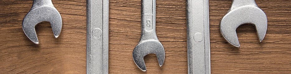 Set of wrenches. Wrenches in several different sizes on natural wooden background, border design panoramic banner 