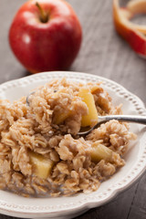 Apple walnut cinnamon oatmeal in a white bowl with a bite in a spoon