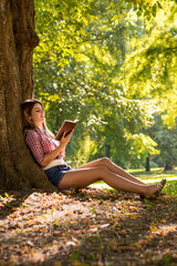 Naklejka na ściany i meble Girl reading book at park