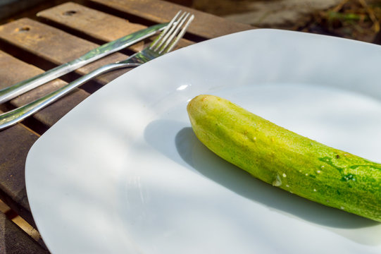 Cucumber on white plate on wooden background