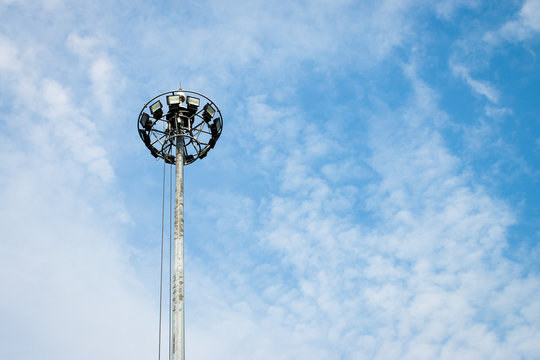 High voltage spotlight pole tower with cloud and blue sky background.
