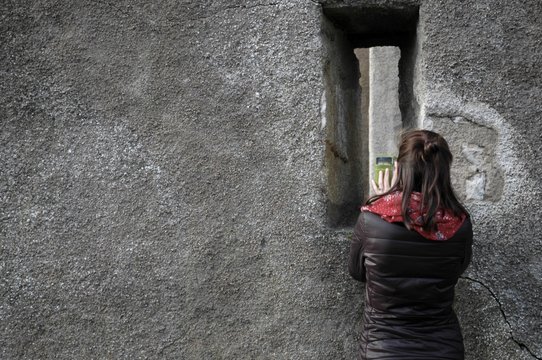 Curious woman taking a photo on a mobile phone of the inside of a castle wall.