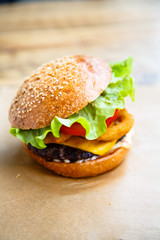 Hamburger with cheese, steak, onion rings and salad.