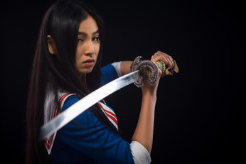 Closeup picture of sword of Asian lady in studio. Pretty lady ready for battle with her opponents isolated on black.