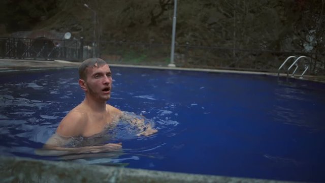 A young handsome man diving and coming out of the hot sulfur spring slow motion