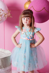Pretty girl child 4 years old in a blue dress. Baby in Rose quartz room decorated holiday.