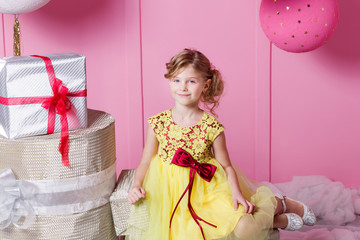 Pretty girl child 6 years old in a yellow dress. Baby in Rose quartz room decorated holiday.