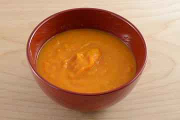 Butternut squash yam and carrot soup in red bowl