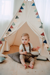 Portrait of lovely little boy happy smiling celebrating 1 year birthday. One year old european little gentleman sitting in a baby tent wigwam © dashamuller