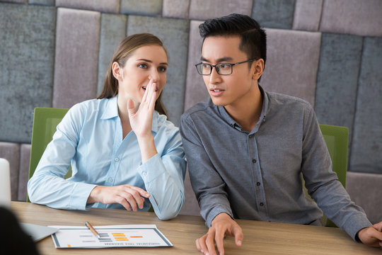 Young woman whispering with colleague