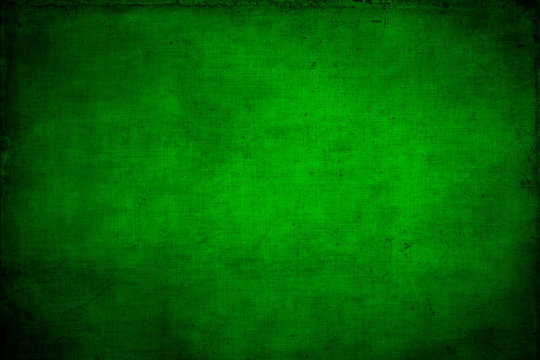 Abstract textured bright green or Christmas  background with bright center spotlight and black vignette border. With a vintage grunge background texture.