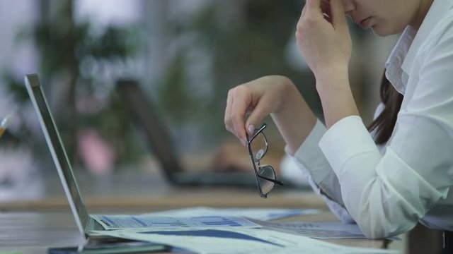 Exhausted woman manager taking off glasses and rubbing eyes, overworked employee