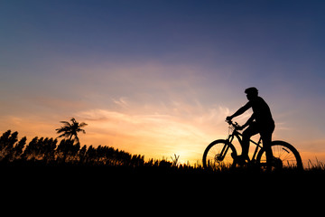 Obraz premium Silhouette the man with mountain bicycle at beautiful sunset