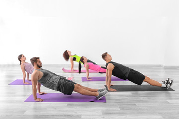 Group of people doing yoga exercises  in gym